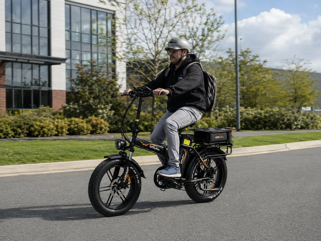Adult rider using an EMOKO C94 cargo e-bike in a real-world urban setting with a helmet and rear cargo rack.
