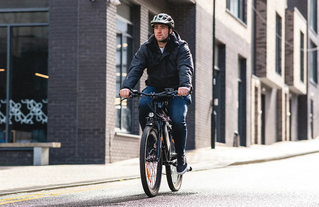 Rider commuting on an EMOKO electric bike in an urban setting where weather, route, speed, assist level, and load can affect battery range