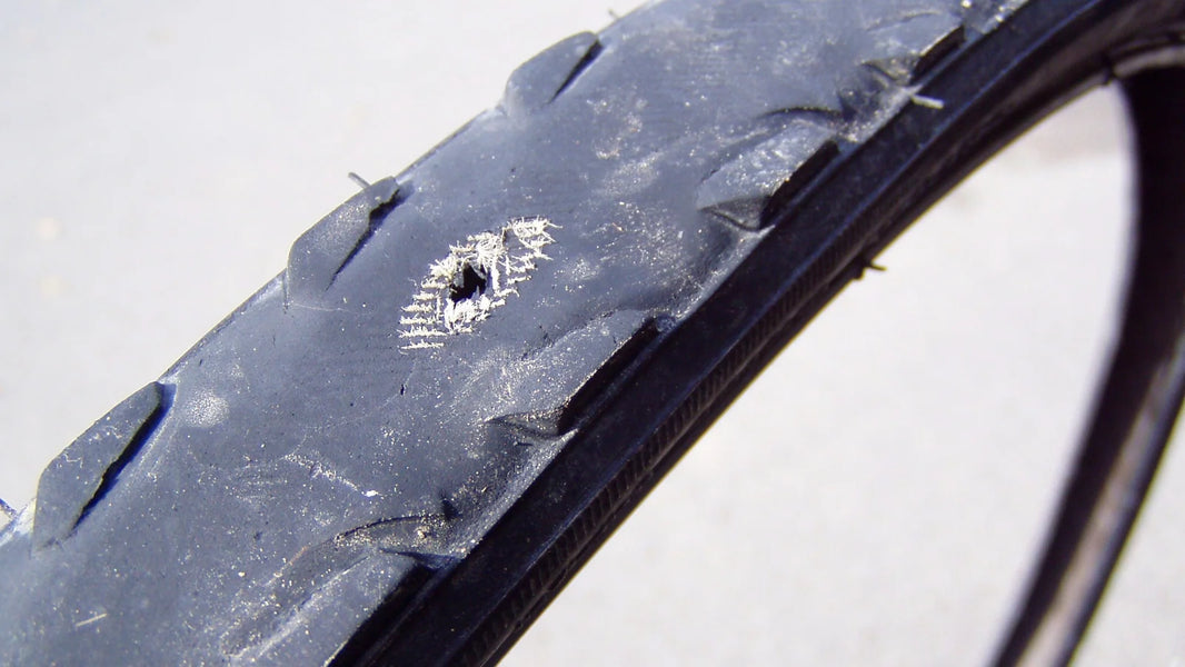 Worn bicycle tire with casing threads exposed through the tread, showing why replacement is needed