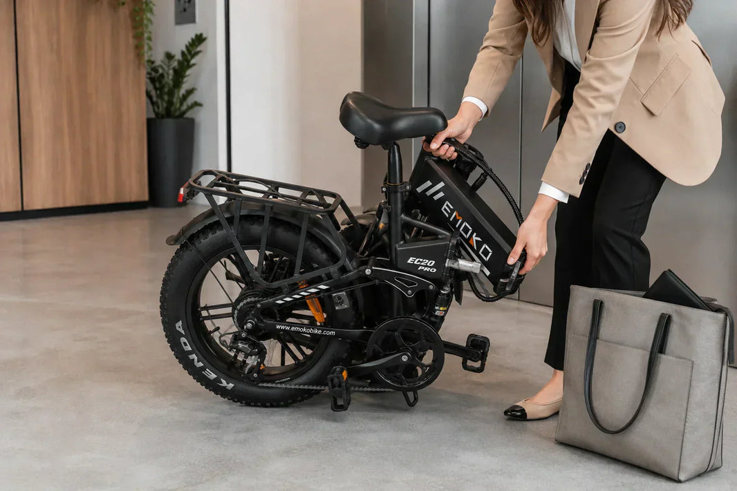 Close-up of a professional folding the EMOKO EC20 Pro e-bike beside an office elevator, showing the compact folding frame and fat tires.