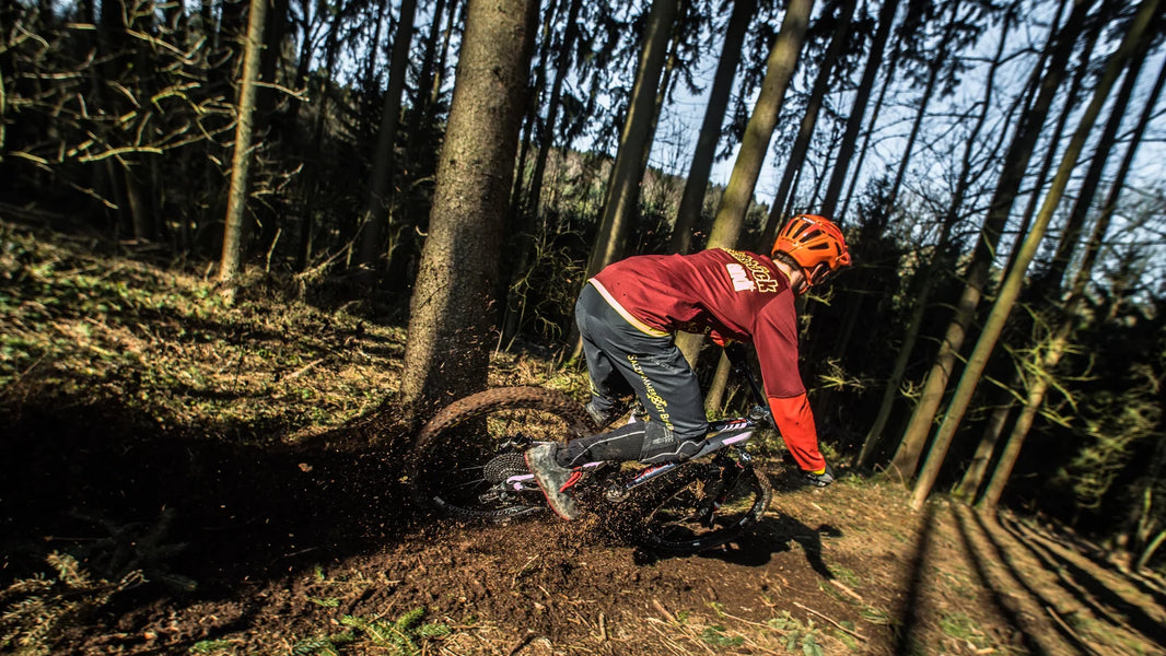 Mountain biker riding through mud on an off-road trail, showing varied conditions affecting MTB tire pressure