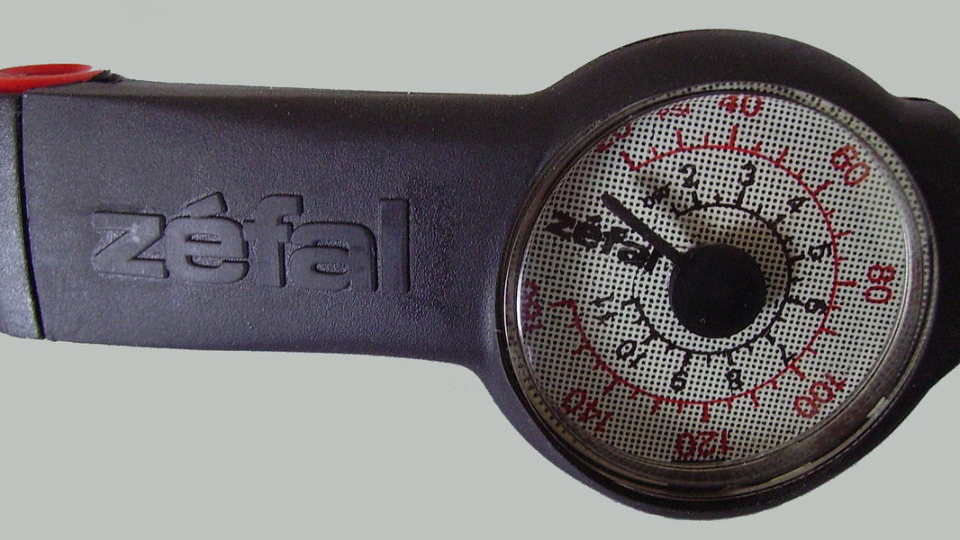 Analog bicycle tire pressure gauge with PSI and bar markings and red Presta and yellow Schrader valve fittings